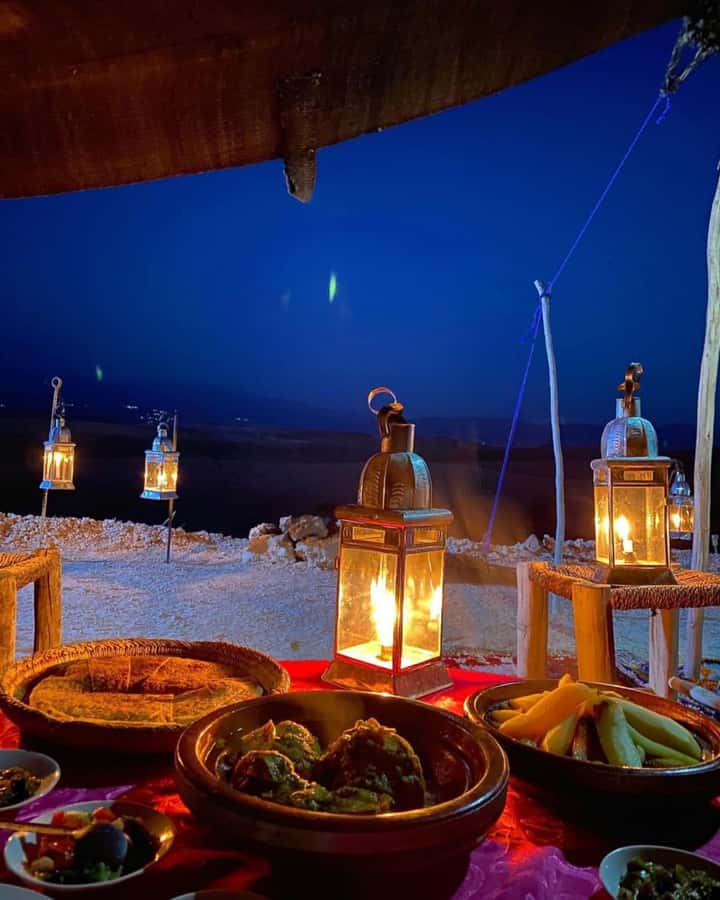 Lanterns set out around a dinner table on the sand in the Agafay desert